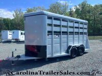 White two-axle livestock trailer with side vents and divider gates on a gravel lot, ready for transport.
