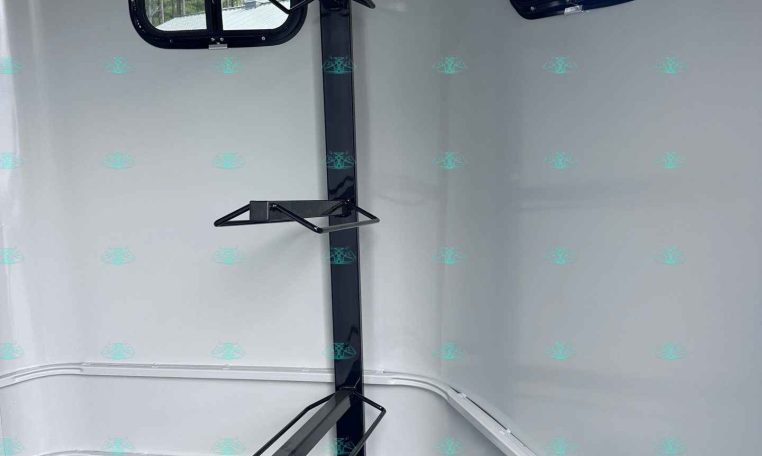 Interior of a cargo trailer with a vertical support post and two fold-down brackets for securing gear, plus two rectangular windows in the side walls.