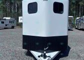White Valle trailer with a black diamond-plate lower section sits on a gravel lot, hitch facing viewer, trees in background.