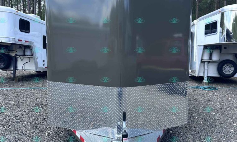 Front view of a gray enclosed cargo trailer with a diamond-plate front, Valley Trailers logo, and hitch with chains on a gravel lot.