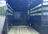 Black horse trailer interior with wooden floor, empty and ready to load, open rear ramp down for access.