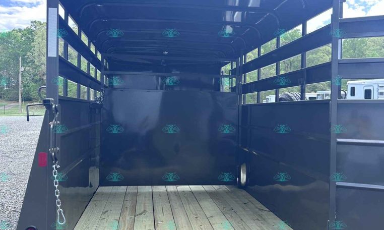 Black horse trailer interior with wooden floor, empty and ready to load, open rear ramp down for access.