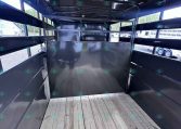 Interior of a black trailer with a wooden plank floor and metal side walls; an internal divider at the far end, empty and ready for cargo.