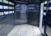 Interior of a black metal cargo trailer with a wooden floor and open back, ready for loading.