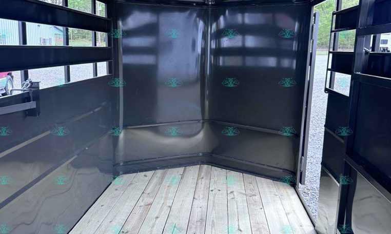 Interior of a black metal cargo trailer with a wooden floor and open back, ready for loading.