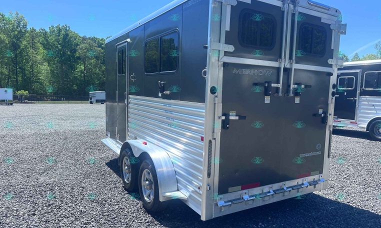 Silver Merhow horse trailer with double rear doors in a gravel lot, trees in the background