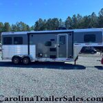 Two‑axle Merhow horse trailer with living quarters, parked on a gravel lot with trees in the background, side door and windows visible