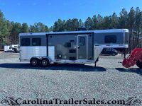 Two‑axle Merhow horse trailer with living quarters, parked on a gravel lot with trees in the background, side door and windows visible