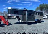 Gooseneck horse trailer with black upper and silver lower panels on a gravel lot, trees in the background.