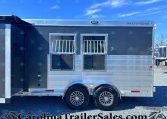 Silver Merhow horse trailer with two barred windows and tandem wheels, parked on a gravel lot under a blue sky.