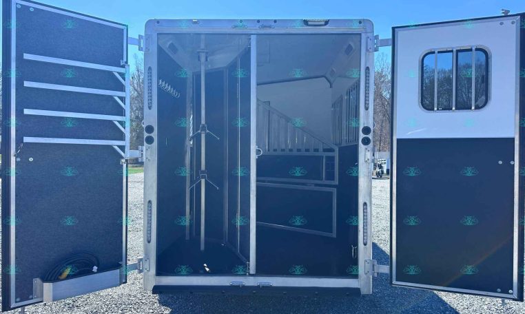 Open horse trailer interior with divider and stalls, tack hooks along the wall visible inside.