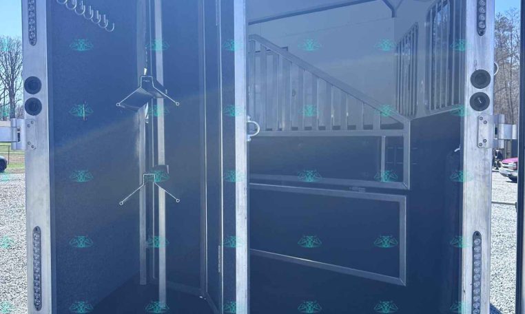 Interior of a horse trailer: tack area with hooks on left and divider, and cabinets with a staircase to an upper area on the right