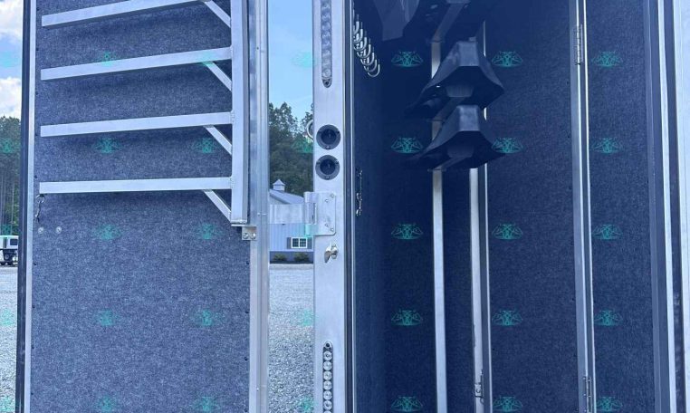 Open trailer showing a vertical auger conveyor inside, likely for grain handling or bulk material transfer.