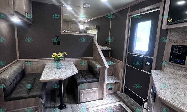 Interior of a modern camper with a U-shaped booth, marble table, and a vase of sunflowers on the table.