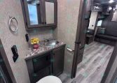 Bathroom in a trailer: vanity with granite countertop, circular sink, mirrored cabinet, towel ring, and toilet.
