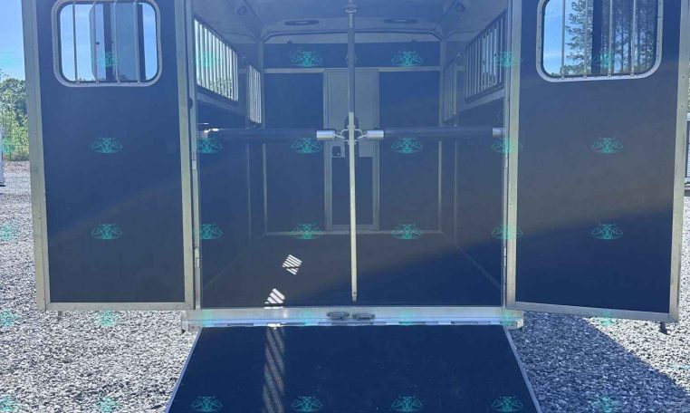 Blue horse trailer with rear doors open and ramp down, showing empty stalls inside.