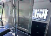 Interior of a metal trailer showing a vertical divider gate and a latching mechanism, with a window and bars visible outside.