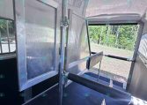 Interior of a metal trailer showing a vertical divider, doorway, and aluminum panels with a black non-slip floor
