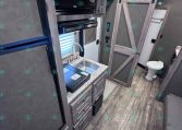 RV kitchenette with microwave above a counter and sink, wood-tone cabinets, and a sliding barn-style door leading to a bathroom area