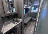 RV kitchen with marble-like countertop, stainless sink, and wood-tone cabinets overheads
