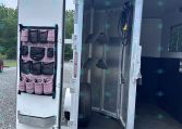 Open aluminum trailer rear with a pink patterned hanging organizer on the door and interior hooks, hoses, and equipment inside.