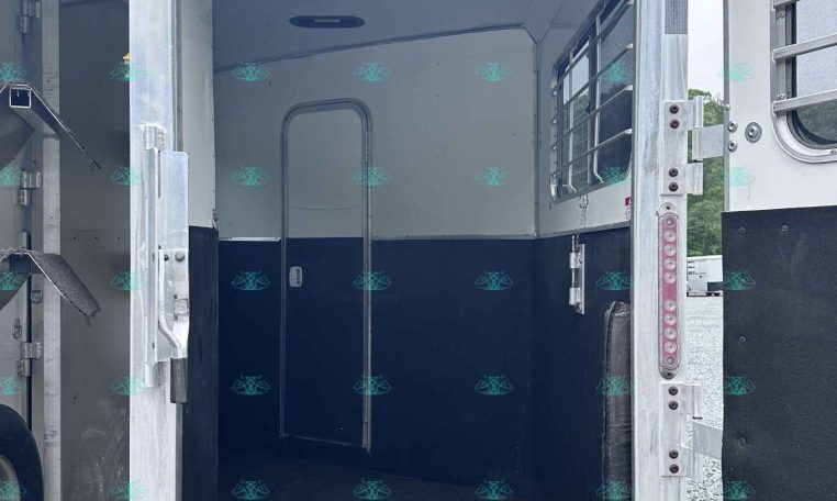 Open horse trailer interior with blue lower walls and metal framing, rear doors swung open.