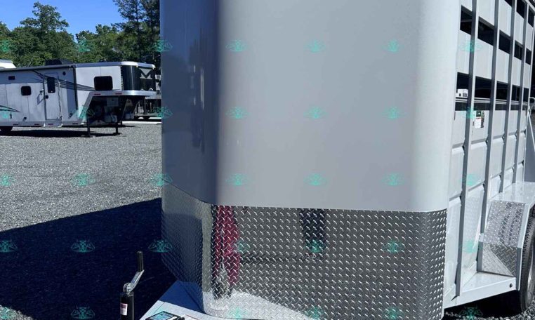 White livestock trailer with curved front and diamond-plate lower panel on a gravel lot