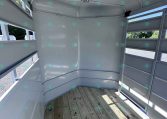 Interior of a light gray horse trailer with curved partitions and vented side openings