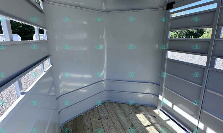 Interior of a light gray horse trailer with curved partitions and vented side openings