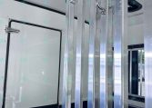Interior view of a trailer with vertical aluminum support rails and a door latch in the frame divider area