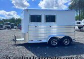 White aluminum trailer with two rectangular windows parked on a gravel lot, other trailers visible in the background.
