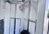 Inside view of a silver enclosed trailer with metal walls, framing, and a visible tire at the floor corner.