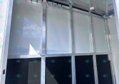 Interior of an aluminum trailer showing metal partitions and a row of hanging hooks inside.
