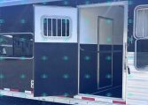 Dark blue trailer side with an open doorway and a small barred window, silver trim, parked on gravel.