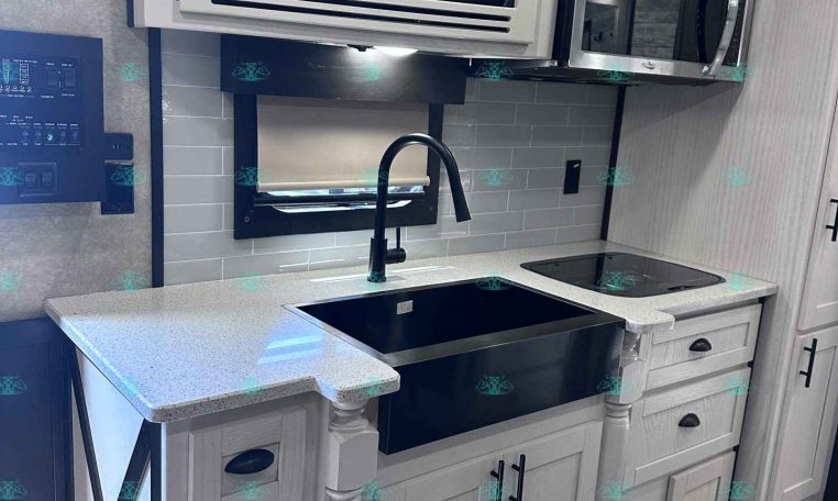 RV kitchen with gray cabinets, stainless microwave above stove, and a modern black faucet over a double sink.