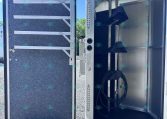 Open trailer door showing a chrome interior with loading ramps and tied-down straps for securing cargo