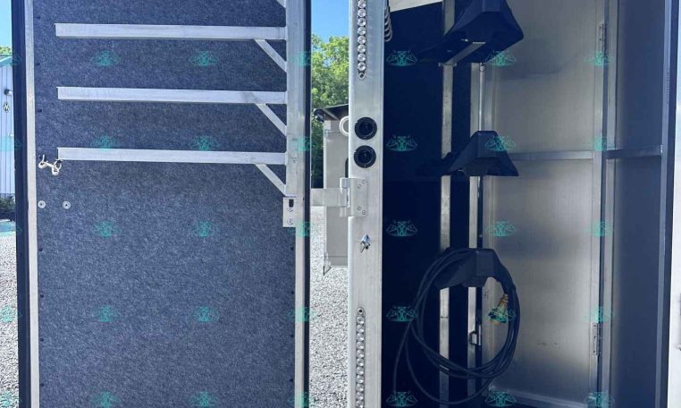 Open trailer door showing a chrome interior with loading ramps and tied-down straps for securing cargo