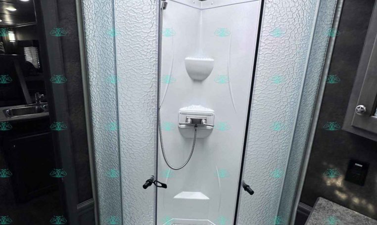 Curved glass shower enclosure in a small RV bathroom with textured frosted doors and a skylight above.