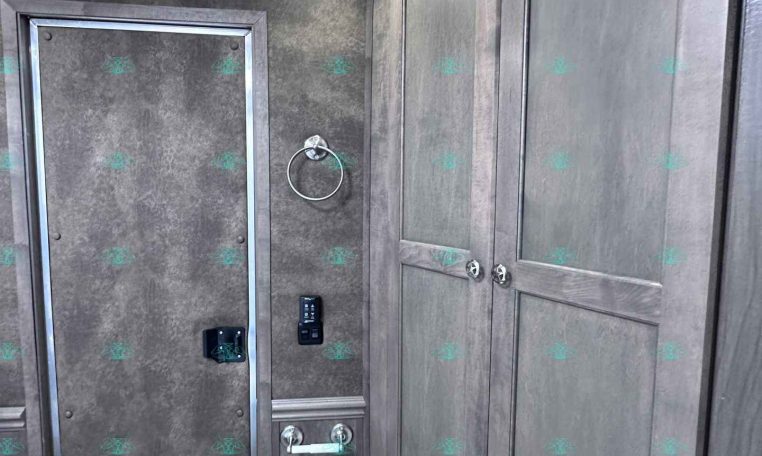 Interior of a travel trailer bathroom with gray cabinetry, a toilet, towel ring, and vented ceiling light.