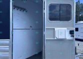 Open trailer doorway revealing empty aluminum interior with hooks along the left wall.
