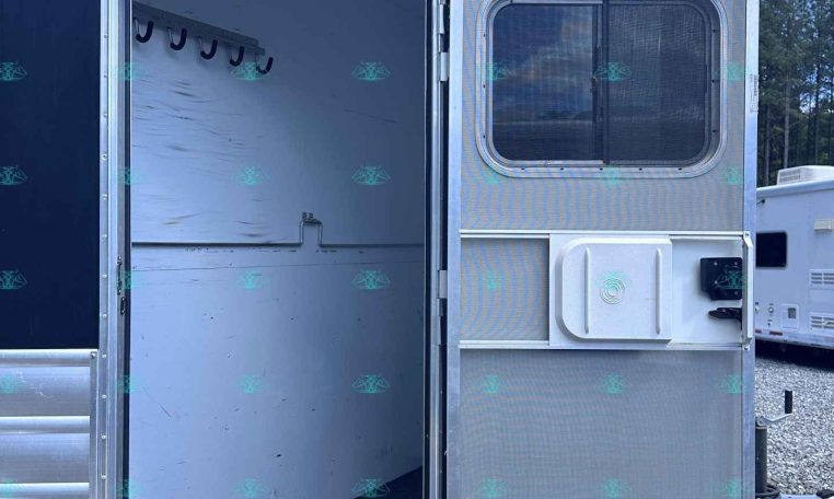 Open trailer doorway revealing empty aluminum interior with hooks along the left wall.