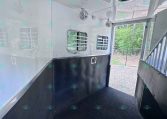 Interior of a white aluminum trailer with ceiling fans, small ventilation windows, and black non-slip flooring