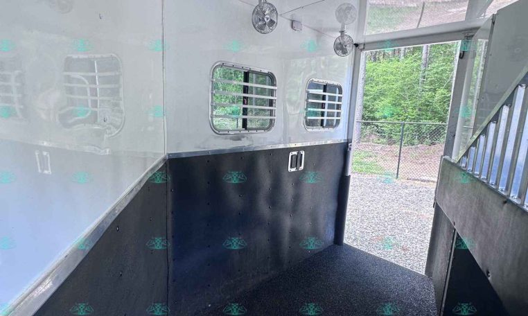 Interior of a white aluminum trailer with ceiling fans, small ventilation windows, and black non-slip flooring