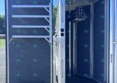 Open rear cargo trailer door showing blue interior walls and a metal staircase inside.