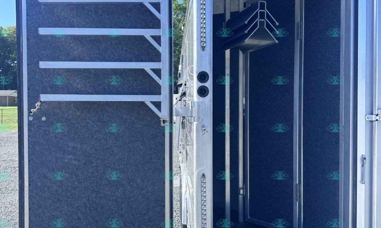 Open rear cargo trailer door showing blue interior walls and a metal staircase inside.