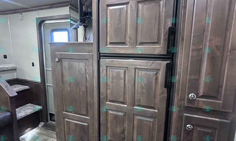 Tall dark-wood RV kitchen cabinet area with a built-in double-door refrigerator (Dometic) and surrounding cabinetry.