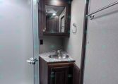 Small trailer bathroom with a dark wood vanity, granite countertop, round stainless sink, and a mirrored cabinet above.
