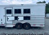 Silver Merhow horse trailer with two small side windows, a side entry door open, and fold-out lower steps on a gravel lot with tandem wheels.