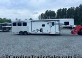 Side view of a white Merhow RV trailer parked on a gravel lot with trees in the background.