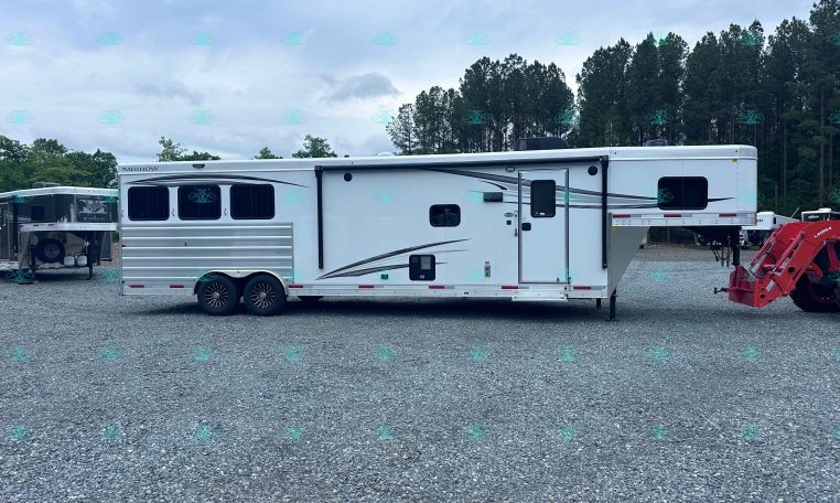 Side view of a white Merhow RV trailer parked on a gravel lot with trees in the background.